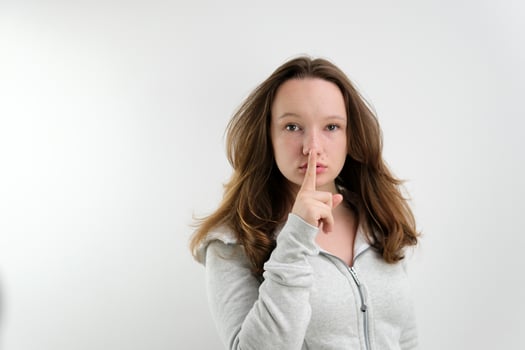Young woman says ssshhh to maintain silence on a white background photo