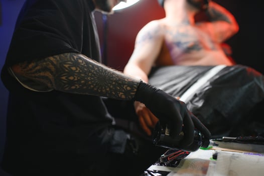 Professional tattoo artist makes a tattoo on a young man hand photo