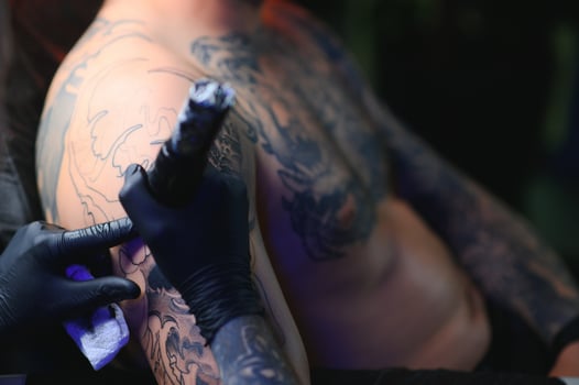 Tattoo artist hands wearing gloves and holding a tattoo machine photo