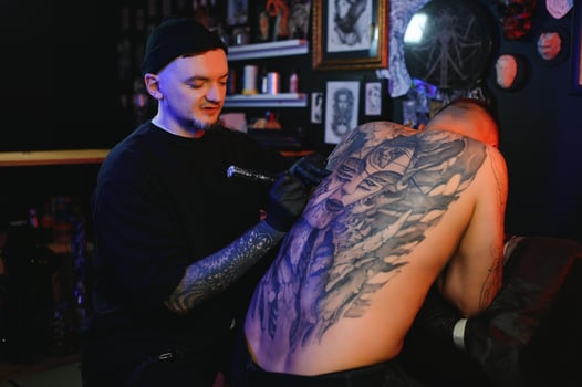 tattoo artist demonstrates the process of getting black tattoo with paint. Master works in black sterile gloves photo