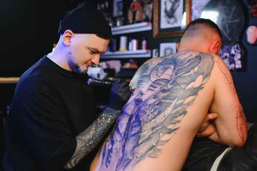 Shot of a tattoo artist hands forming perfect lines on man back with ink photo