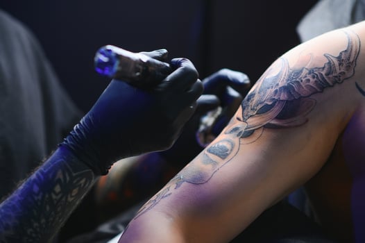 Tattoo artist hands wearing gloves and holding a tattoo machine photo