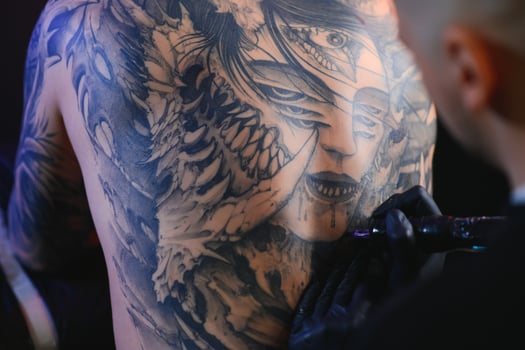Shot of a tattoo artist hands forming perfect lines on man back with ink photo