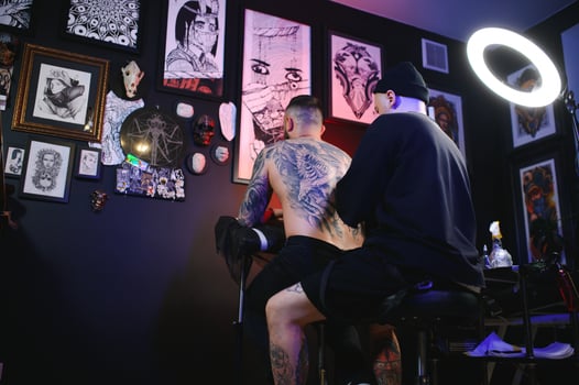 tattoo artist demonstrates the process of getting black tattoo with paint. Master works in black sterile gloves photo