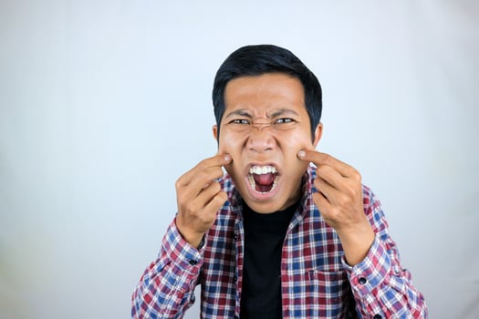 Asian man's annoyed expression touches his cheek because he is chubby photo