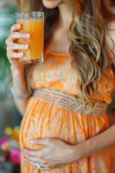 happy pregnant woman drinking green vegetable juice or smoothie at home. photo