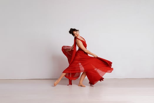 Dancer in a red flying dress. Woman ballerina dancing on a white studio background photo