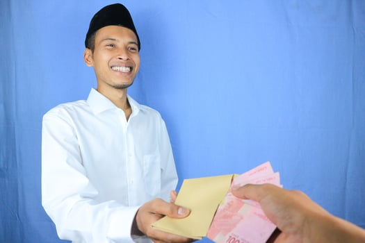 Smiling expression of Asian Muslim man giving money for helping, donation or zakat photo