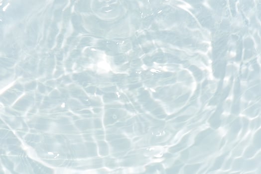 Blue water with ripples on the surface. Defocus blurred transparent blue colored clear calm water surface texture with splashes and bubbles. Water waves with shining pattern texture background. photo