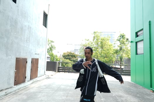 ASian man is dancing in hip hop style at outdoor space. Professional solo dancer is performing in public area. photo