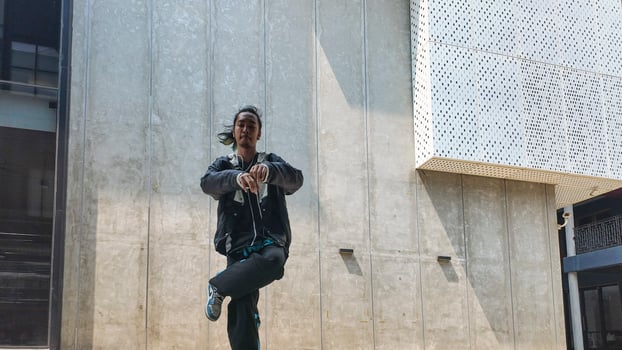 ASian man is dancing in hip hop style at outdoor space. Professional solo dancer is performing in public area. photo