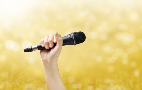 hand holding microphone The background is golden bokeh. photo