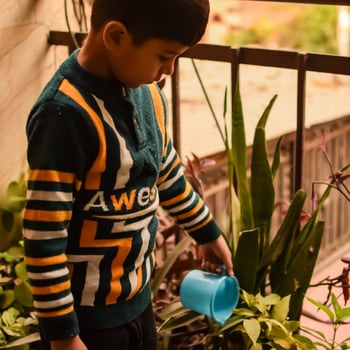 Cute 5 year old Asian little boy is watering the plant in the pots located at house balcony, Love of sweet little boy for the mother nature during watering into plants, Kid Planting photo