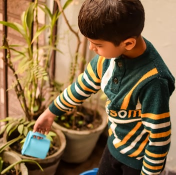 Cute 5 year old Asian little boy is watering the plant in the pots located at house balcony, Love of sweet little boy for the mother nature during watering into plants, Kid Planting photo