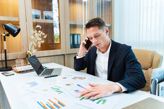 Caucasian business manager using phone to call customer while analyzing the sales report from marketing team for business income and financial management usage photo