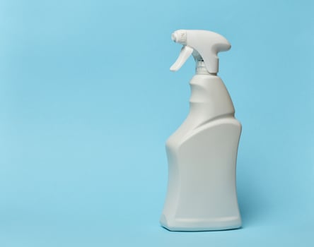 White plastic bottle with spray on a blue background, container for household chemicals photo
