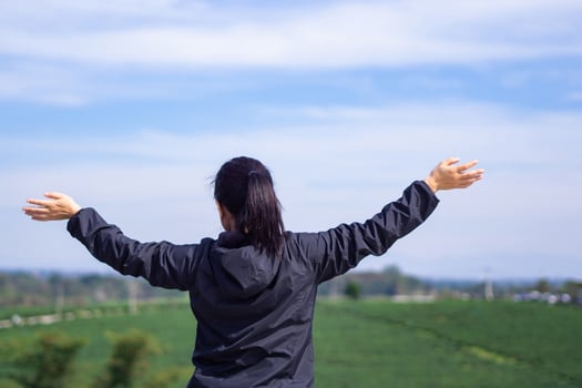Back view of a woman hands up while standing looking at the tea plantation. Space for text. Relaxation concept photo