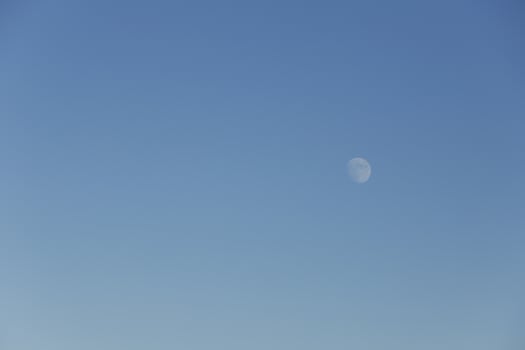 moon shines in a bright blue sky photo