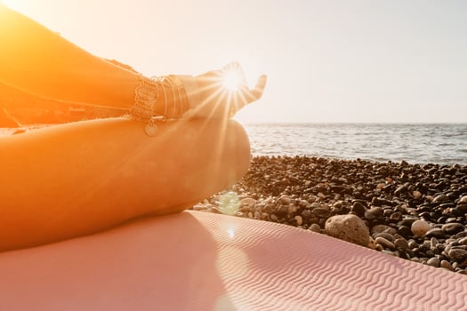 Woman sea yoga. Happy woman in white swimsuit and boho style braclets practicing outdoors on yoga mat by sea on sunset. Women yoga fitness routine. Healthy lifestyle, harmony and meditation photo