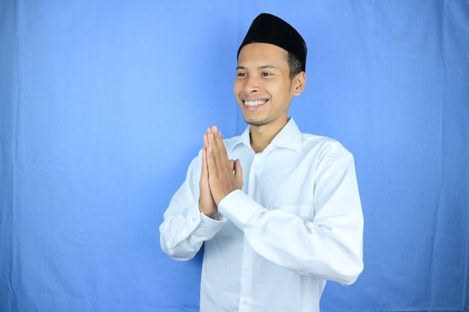 Smiling expression Asian Muslim man greeting Ramadan and Eid Al Fitr celebration on white background photo