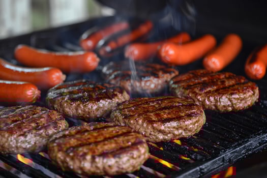 Barbecue grill sizzling with juicy burgers and hotdogs, staple of summer gatherings photo