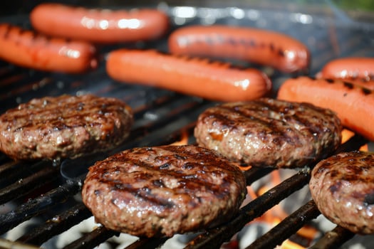 Barbecue grill sizzling with juicy burgers and hotdogs, staple of summer gatherings photo