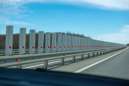 A road with a long line of metal posts with red hearts on them. The road is empty and the sky is clear. photo