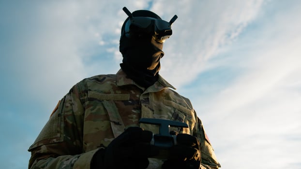Man In Military Uniform With VR Headset Pilots A Drone Outdoors To Missiles photo