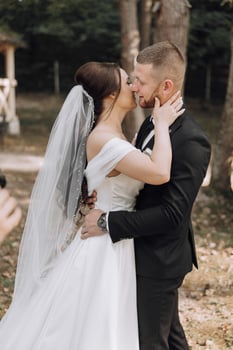 A bride and groom are kissing in a forest photo