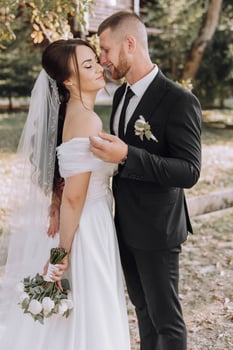 A bride and groom are standing together in a field photo