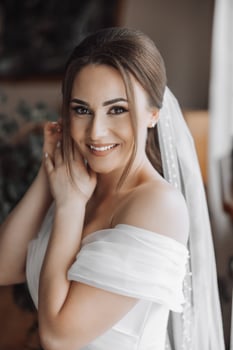 A woman is posing for a picture with a white veil on her head photo