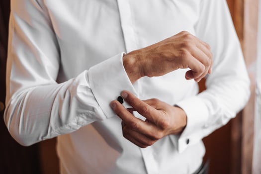 A man is getting dressed in a white shirt and black cufflinks photo