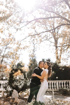 A couple is kissing in front of a tree with leaves that are changing colors photo