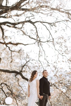 A couple standing in front of a tree with leaves falling photo