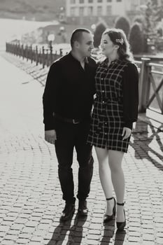 A man and woman are standing on a brick walkway, smiling at the camera photo