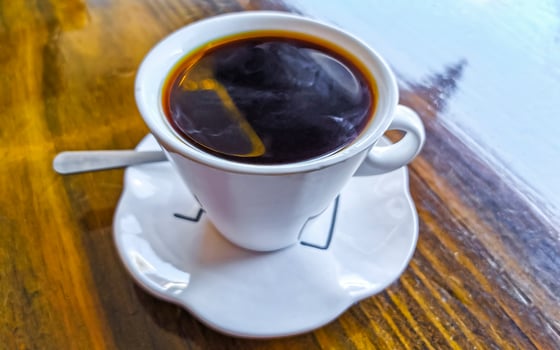 White cup of black Americano coffee on a wooden table. photo