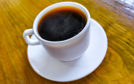 White cup of black Americano coffee on a wooden table. photo