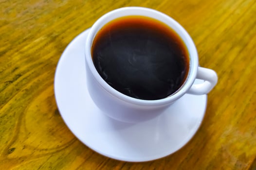 White cup of black Americano coffee on a wooden table. photo