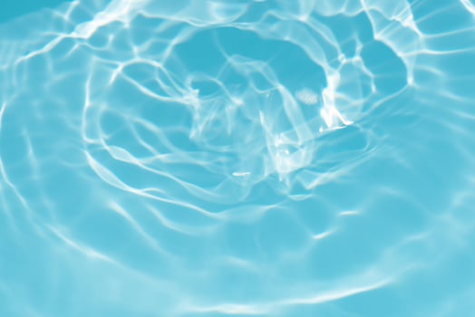 Blue water with ripples on the surface. Defocus blurred transparent blue colored clear calm water surface texture with splashes and bubbles. Water waves with shining pattern texture background. photo