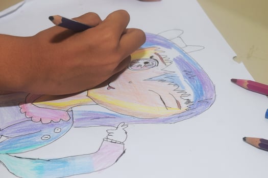 A small child is drawing and coloring an work made on paper photo