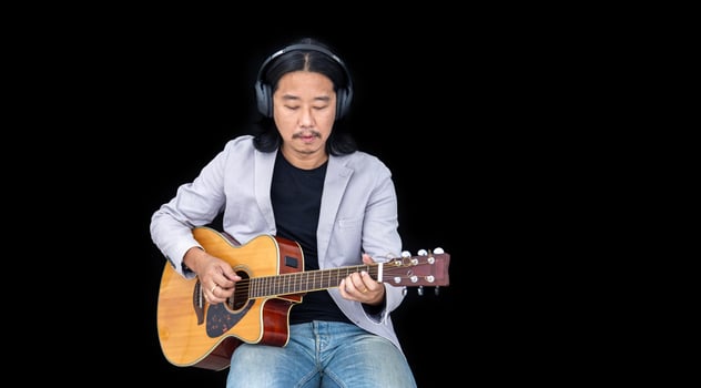 Asian artist singing song and playing acoustic guitar on black background for live acoustic concert and music related photo