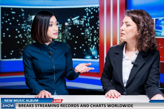 Journalists team talk about new music album, women night show hosts reveal song breaking top charts and records at global scale. Newscasters discuss about streaming and selling success. photo