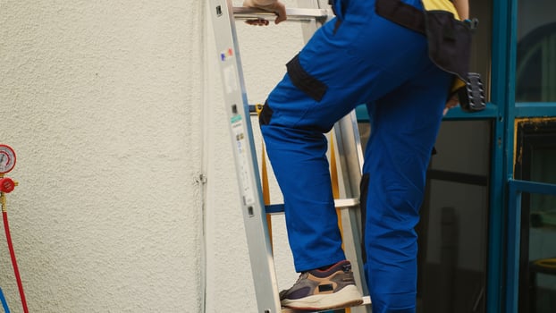 Expert repairman in professional uniform with technical equipment climbing folding ladder to do maintenance on rooftop air conditioner. Efficient technician commissioned to checkup on hvac system photo
