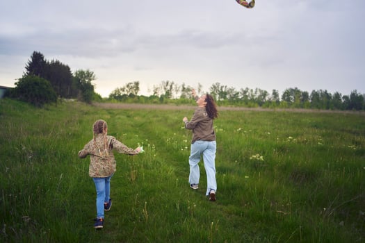 two little sisters and mother run and launch a kite in a field photo