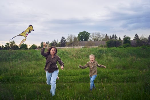 two little sisters and mother run and launch a kite in a field photo