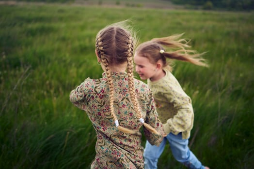 beautiful blonde sisters play with a dandelion in the field photo