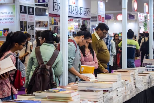 Delhi, India, February 17 2024 - Various age group people reading variety of Books on shelf inside a book-stall at Delhi International Book Fair, Books in Annual Book Fair at Bharat Mandapam complex photo