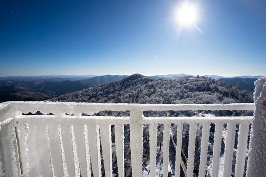 The balcony railing is covered with frost with snow-white background. View from the balcony during a snowfall. Selective focus. photo