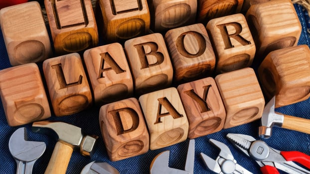 Wooden letter blocks spelling Labor Day with tools on blue denim fabric background photo