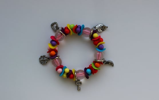 Stacked Handmade Bracelet With Small Silver Charms On A White Surface photo